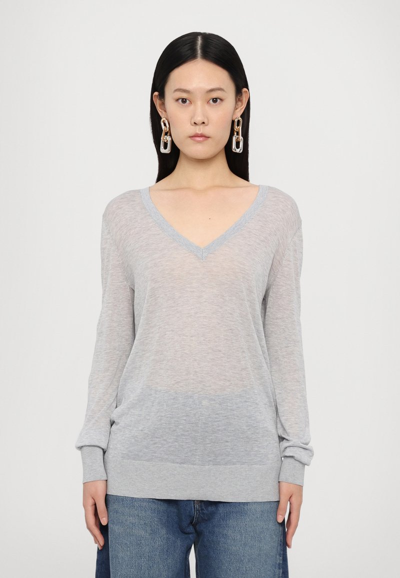 Pullover en V gris clair avec des manches longues, fabriqué dans un matériau doux et transparent, présentant une dégradation de couleur vers l'ourlet.