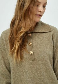 Beige kudum särk kraega, kolme kuldse nupuga, soonikuvarruga ja pehme, tekstuurse viimistlusega.