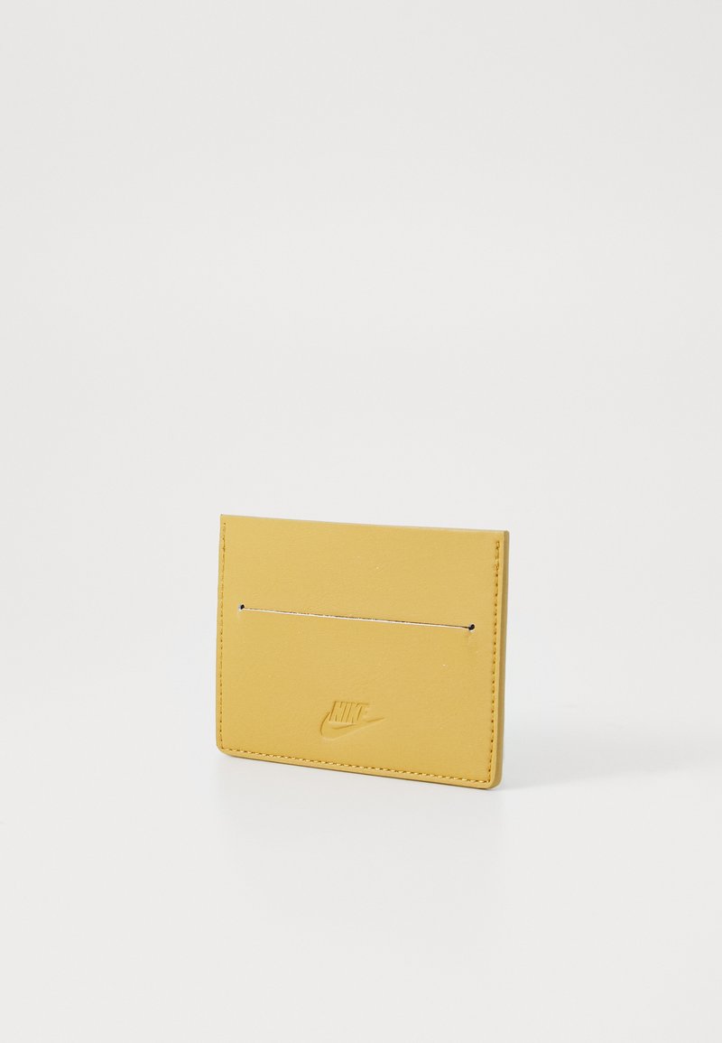 Tarjetero de cuero amarillo con textura suave, que presenta un logo estampado y dos compartimentos para tarjetas en la parte frontal. Diseño minimalista.