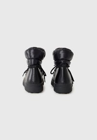 Black padded ankle boots with a smooth leather finish, round toe, and textured rubber soles. Features adjustable laces and folded collar.