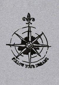 Tessuto grigio con un design di bussola ricamato in nero e il testo "SEGUITI I TUOI SOGNI" disposto in modo curvo attorno ad essa.