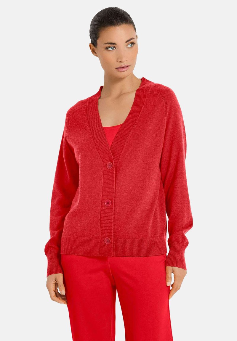 Rode gebreide cardigan met een V-hals, vijf knopen en geribde manchetten en onderrand. Gemaakt van een zachte stof, gecombineerd met een bijpassend rood top.