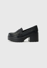 Mocassins pretos em plataforma com um cabedal de couro liso, apresentando detalhes decorativos em forma de tiras e uma sola de borracha grossa e texturizada.