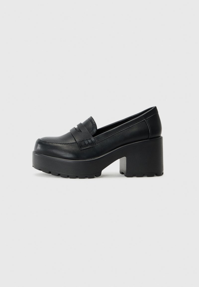 Mocassins pretos em plataforma com um cabedal de couro liso, apresentando detalhes decorativos em forma de tiras e uma sola de borracha grossa e texturizada.