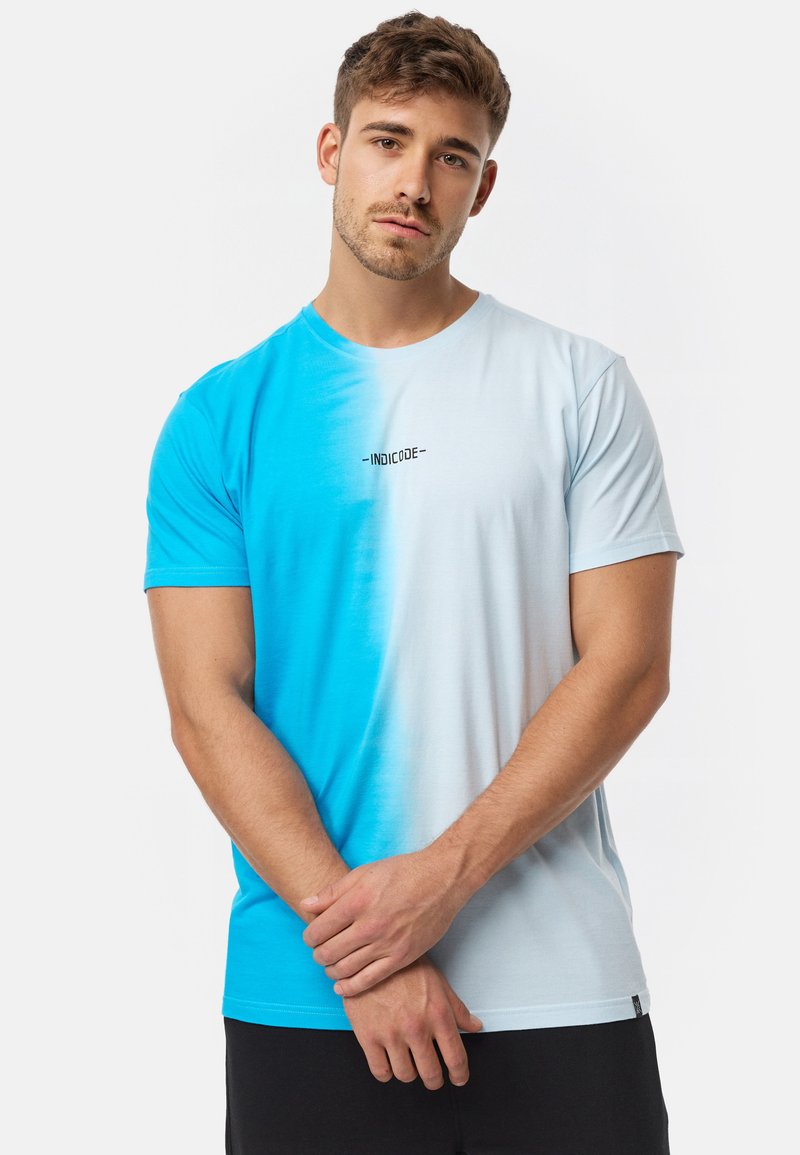 Camiseta azul claro con degradado a azul brillante. Presenta un escote redondo y un pequeño logo "INDICODE" impreso en el pecho.