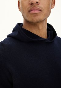 Granatowy hoodie wykonany z miękkiej dzianiny o luźnym kroju, wyposażony w kaptur ze sznurkiem i minimalnymi szwami dla schludnego wyglądu.