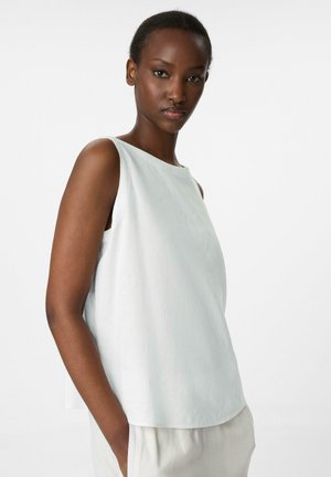 Haut sans manches bleu clair avec un col bateau, fabriqué dans un tissu texturé, présentant une coupe ample et de légentes fentes latérales pour plus de confort.