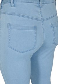 Vaqueros de tiro alto en azul claro con una silueta ajustada, que cuentan con dos bolsillos traseros y costuras de contraste a lo largo de las costuras. Textura de denim suave.