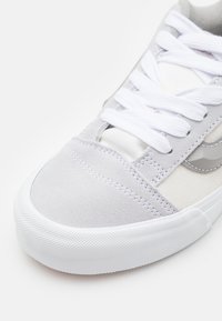 Graue Wildledersneaker mit weißen Schnürsenkeln und einer strukturierten Gummisohle. Verfügt über ein schlichtes Design, gestickte Details und ein glattes Stoffobermaterial.