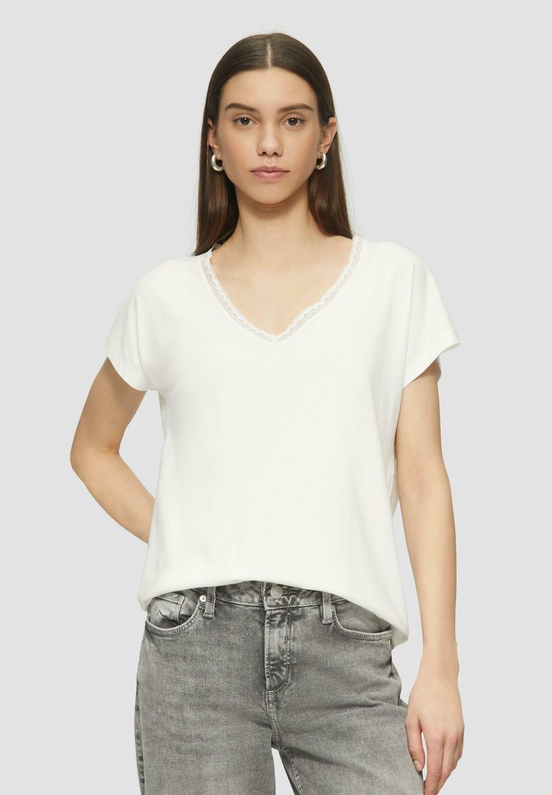 Weißes, kurzärmeliges V-Ausschnitt-T-Shirt mit Spitze am Ausschnitt, aus weichem Stoff und in bequemer Passform, kombiniert mit grauen hochgeschnittenen Jeans.