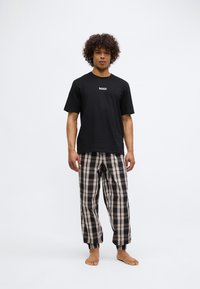 T-shirt negru din bumbac cu logo-ul "BOSS", asortat cu pantaloni de pijama în carouri, de culoare bleumarin, crem și bej, având un brâu elastic și manșete.