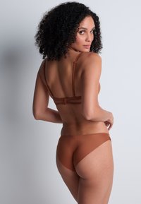 Ensemble de lingerie marron avec bretelles ajustables, fermeture à crochets et œillets, et un tissu lisse et extensible avec un design sans coutures.