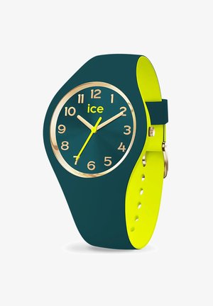 Orologio in silicone verde con una ghiera color oro, grandi numeri gialli e due lancette gialle su un quadrante verde scuro. Inclusi accenti di cinturino giallo.