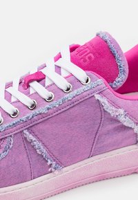 Baskets violettes et roses avec lacets blancs, détails en tissu effiloché et œillets métalliques sur une semelle en caoutchouc texturée.