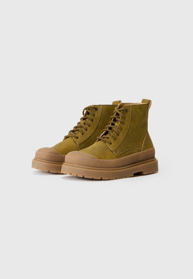 Olive green suede ankle boots with round toe, chunky tan rubber sole, and lace-up design. Features a reinforced toe cap and back pull tab.