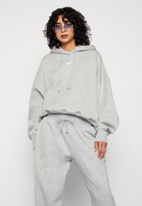 Grauer Hoodie mit einer Vorderstasche, einer Kapuze mit Kordelzug und gerippten Bündchen. Kombiniert mit passenden grauen Jogginghosen mit elastischem Bund.