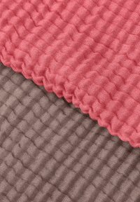 Strukturerede stofprøver i pink og grå, med et gitterlignende mønster og forhøjede sektioner for taktil kontrast.
