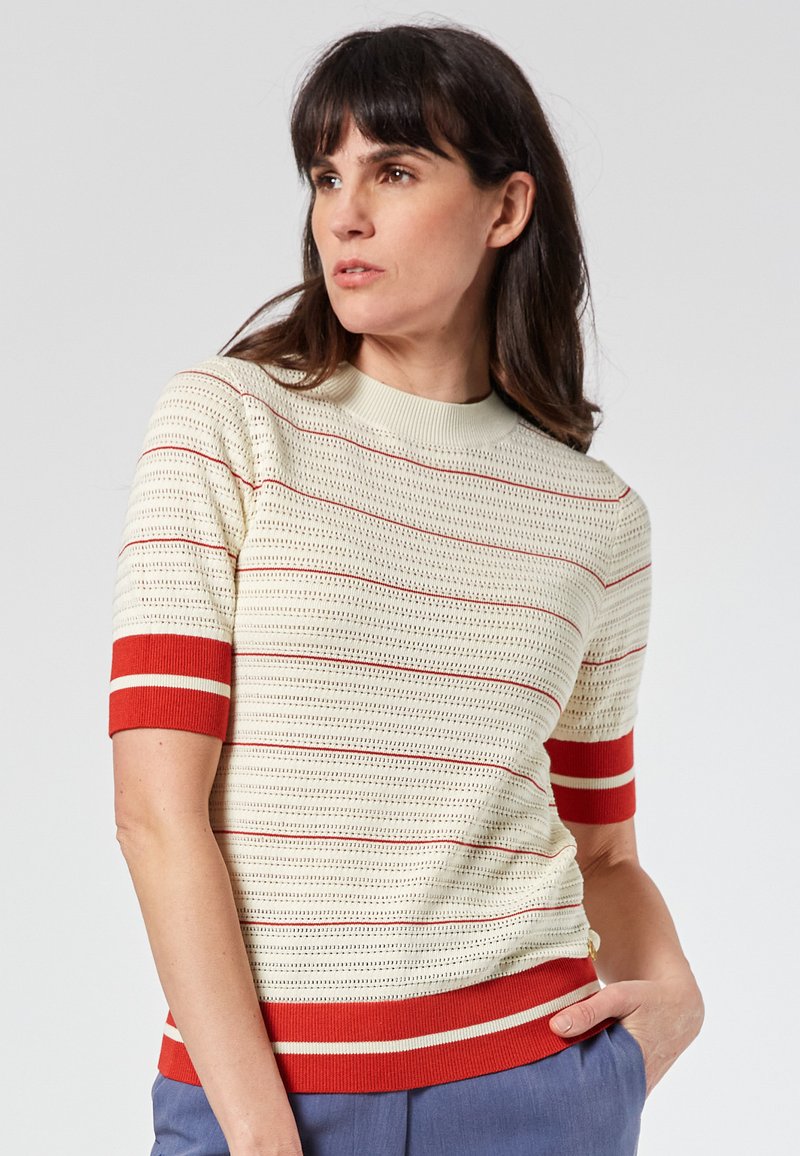 Knit short-sleeve sweater in cream with red stripes. Features a ribbed neckline and cuffs, with a textured pattern throughout.