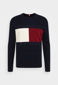 Pull en tricot bleu marine à manches longues, présentant un design tricolore horizontal : blanc, rouge et bleu marine, avec le texte « HILFIGER NEW YORK ».