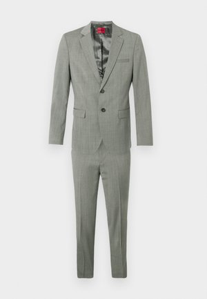 Vaaleanharmaa puku, jossa on lohkoreunus, yksirivinen bleiseri ja tasapohjaiset housut. Valmistettu teksturoidusta kankaasta, jossa on sileä vuori.