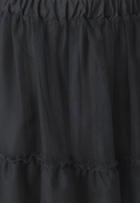 Fustă din tul negru cu un brâu elastic plisat, volane suprapuse și o textură transparentă, oferind un aspect ușor și aerisit.