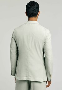 Light gray suit jacket with a textured finish, single vent at the back, and button accents on the cuffs, viewed from the back.