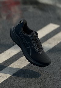 Black athletic shoe featuring a smooth, textured upper, cushioned sole, and subtle branding. Designed for comfort and performance.