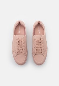 Baskets synthétiques roses avec une texture lisse, un bout arrondi et un design à lacets. Caractéristiques : logo sur la semelle intérieure et accents de coutures sur les côtés.