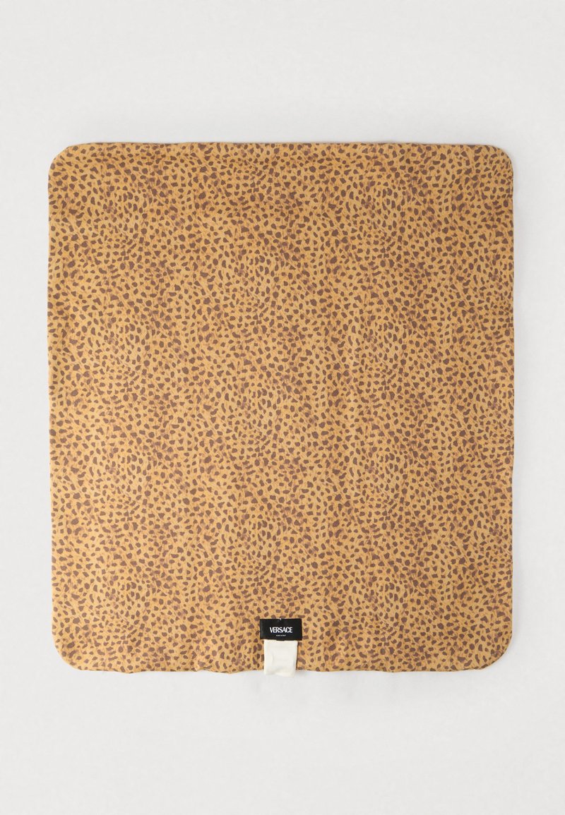 Ύφασμα με τύπωμα λεοπάρδαλης σε ανοιχτό καφέ χρώμα με σκουρότερες κηλίδες, με στρογγυλεμένες γωνίες και εμφανή ετικέτα Versace.