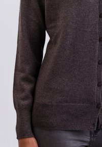 Mörkgrå cardigan i mjuk ull med knappstängning framtill, ribbade ärmslut och fåll, med en slät textur och figurnära silhuett.