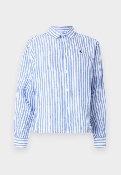 Chemise à manches longues avec boutons, rayures verticales bleues et blanches, et petit logo brodé bleu foncé sur la poitrine gauche.