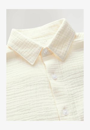 Cămașă albă texturată, cu guler și nasturi din plastic neted, având linii orizontale din material pentru un detaliu suplimentar.