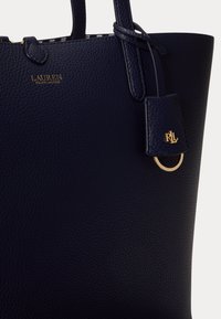 Τσαντάκι ώμου από ναυτικό χοντρό δέρμα με διπλές λαβές, χρυσό λογότυπο "Lauren Ralph Lauren" και δερμάτινη ετικέτα με χρυσό έμβλημα RLL και λεπτομέρεια δαχτυλιδιού.