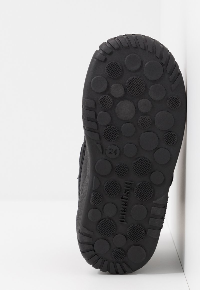 Czarna podeszwa buta z teksturowaną powierzchnią o okrągłych i kwadratowych wzorach, solidny uchwyt i trwały materiał gumowy.