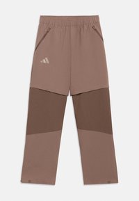 Καφέ αθλητικό παντελόνι με μπλοκ χρώματος, ελαστική μέση, τσέπες με φερμουάρ στο πλάι και μικρό λογότυπο Adidas στο αριστερό πάνω μηρό.