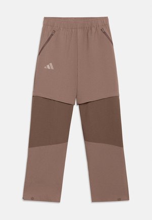 Brown color-blocked athletic pants with elastic waistband, zippered side pockets, and a small Adidas logo on the upper left thigh.