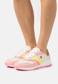 Multicolored sneakers featuring pink and yellow accents, fabric and suede materials, rounded toe, and white laces with a logo on the side.