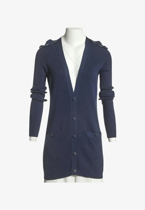 Cardigan long bleu marine en maille texturée, fermeture boutonnée, deux poches avant et détails de boutons aux épaules sur un mannequin blanc.