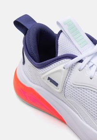 White athletic shoe with mesh upper, purple accents, and a bright orange and pink sole. Features a PUMA logo and rear pull tab.