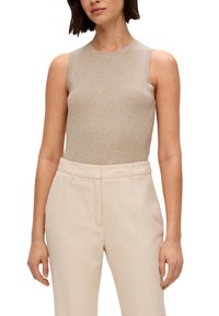 Beige mouwloze top van rib gebreid materiaal met een ronde halslijn, gecombineerd met op maat gemaakte crèmekleurige broek met voorplooien en zijzakken.