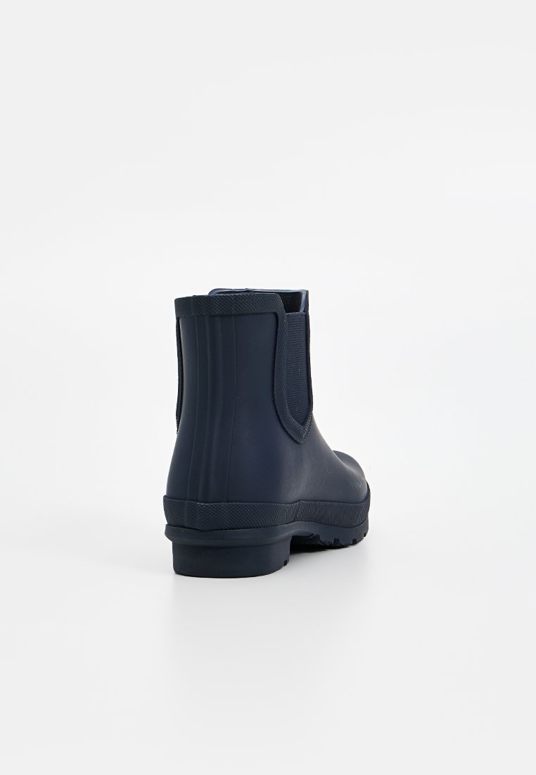 Dunkelblaue Gummistiefel bis zum Knöchel mit elastischen seitlichen Einsätzen, einer strukturierten Gummisohle und vertikalen Rillen auf der Rückseite für zusätzlichen Halt.