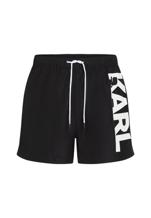 Fekete úszónadrág könnyű anyagból, fehér díszítőzsinórral és nagy "KARL" logóval az oldalon. Simaság jellemzi.