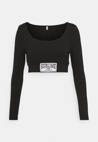 Black cropped long-sleeve top with a square neckline and a white "SUBLIME 1995 NEW YORK STATE" patch on the front. Smooth cotton fabric.