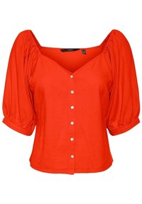 Blouse en coton rouge avec un décolleté en V, des manches bouffantes et six boutons blancs sur le devant. Texture lisse et coupe ample.