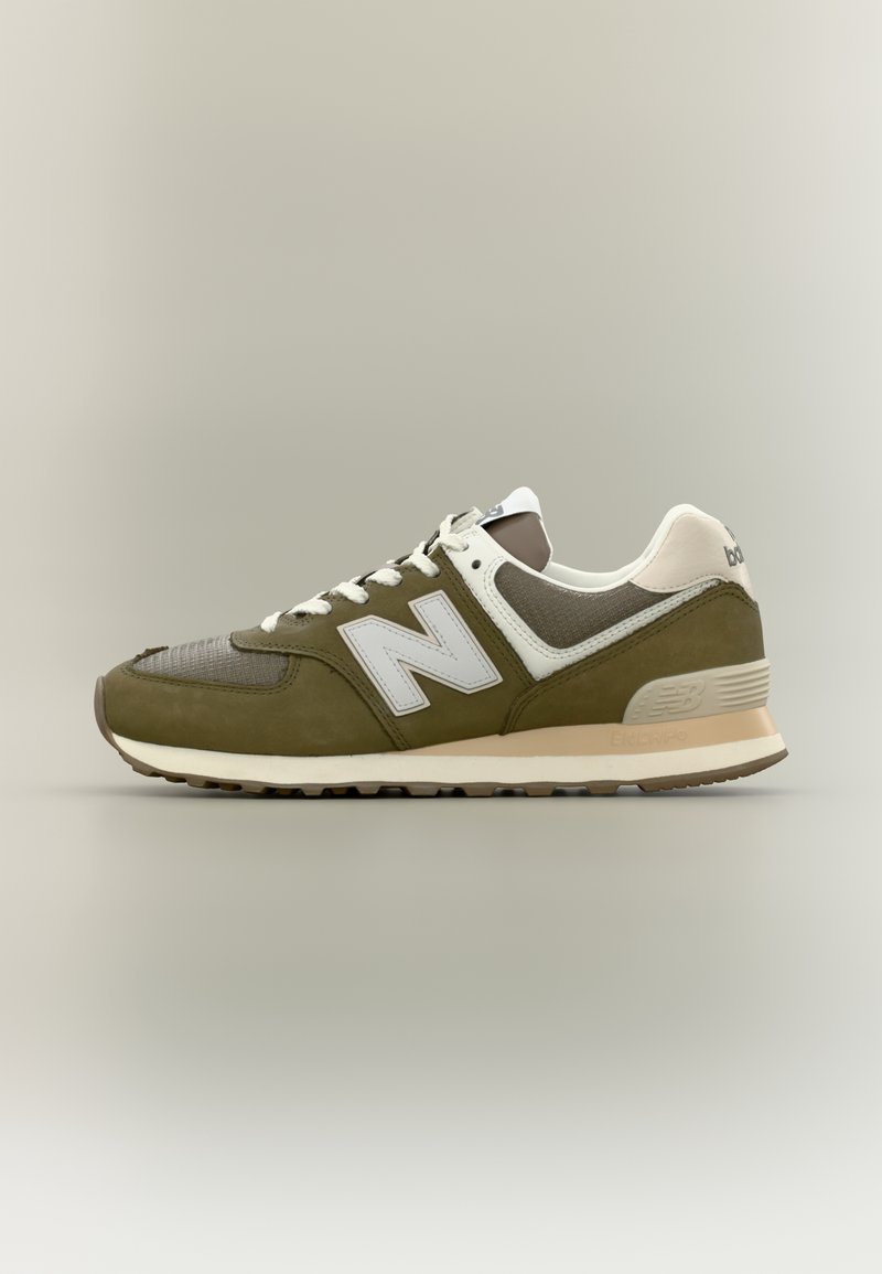 Basket New Balance vert olive et beige avec lacets blancs et logo, affichée sur un fond clair uni.