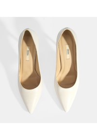 Escarpins blancs à bout pointu en cuir lisse, présentant un design sans couture et une doublure intérieure subtile. Esthétique propre et minimaliste.