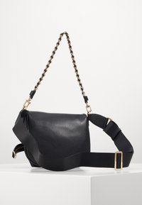 Black leather shoulder bag with a textured surface, featuring a chain and fabric strap, gold hardware, and adjustable buckle.
