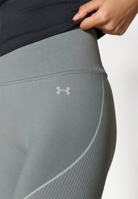 Γκρι αθλητικό κολάν με ομαλή υφή, με διακριτικό σχέδιο ρίγας και μικρό, λευκό λογότυπο Under Armour στη μέση.