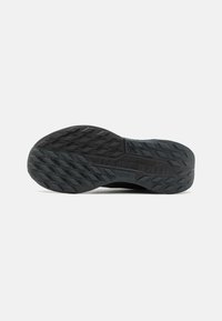 Zwarte rubberen buitenzool met een getextureerd grippatroon, voorzien van hoekige noppen voor tractie en een glad centraal gebied voor comfort.