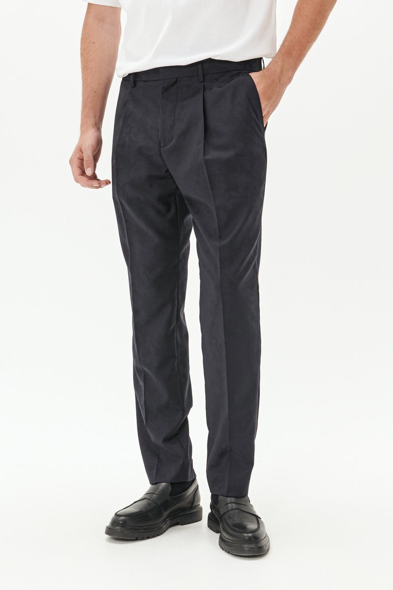 Pantaloni blu navy con un motivo testurizzato sottile, fit su misura e frontale piatto. Presentano tasche laterali e una vita classica. Abbinati a scarpe nere.